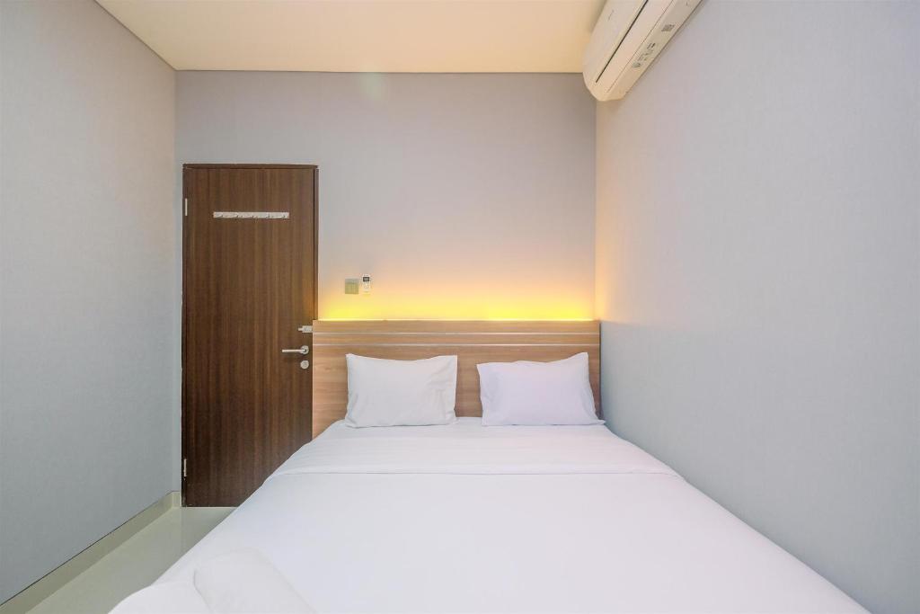 Fully Furnished with Cozy Design 2BR Apartment Transpark Cibubur By Travelio في ديبوك: غرفة نوم بسرير كبير مع ملاءات بيضاء