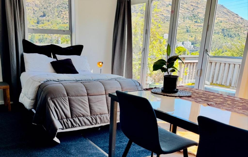 a bedroom with a bed and a table and chairs at Airport Guesthouse in Queenstown