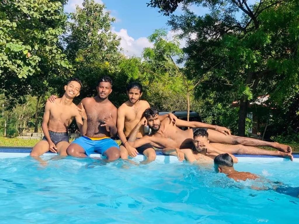 a group of men sitting in a swimming pool at Suriya Cottage Family Resort in Habarana