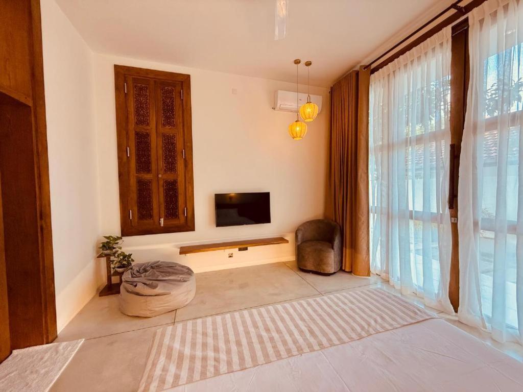 a living room with a tv and a large window at Madiha Venus in Matara
