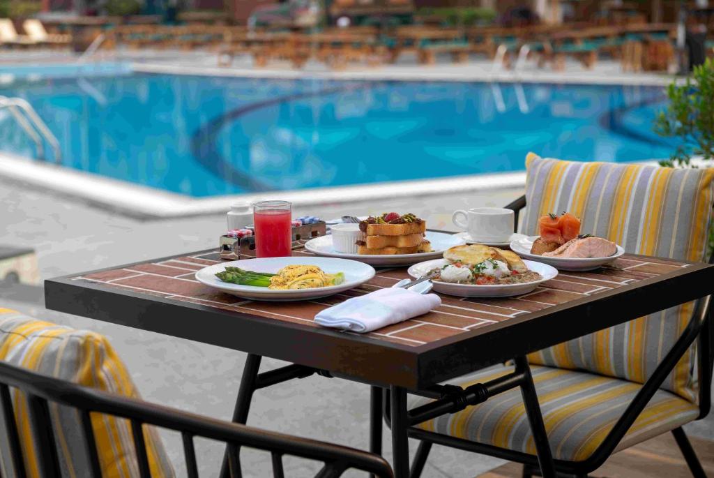 a table with plates of food on it next to a pool at Le Royal Meridien Abu Dhabi in Abu Dhabi