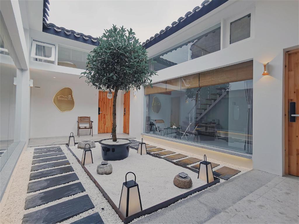 Suzhou Xugusu B&B-Guanqian Street Pingjiang Road Branch في سوتشو: بيت فيه شجره وسط ساحه