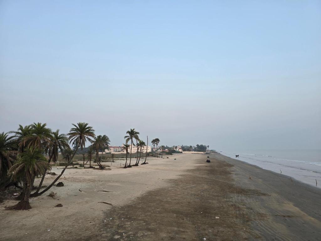an empty beach with palm trees and the ocean at Ricardo Beach Resort in Mandarmoni