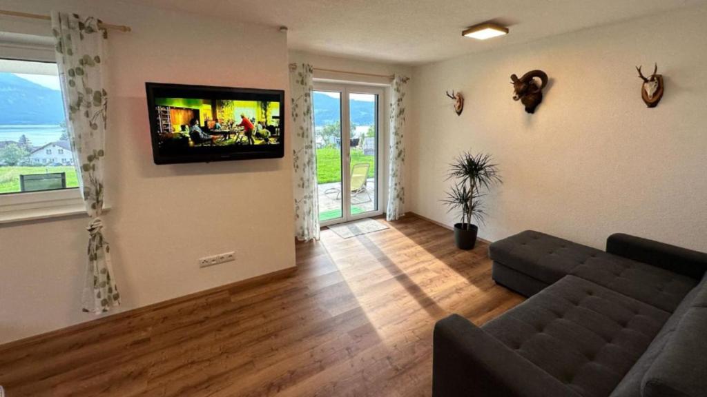 a living room with a couch and a flat screen tv at Wild und Wald Ferienwohnung in Steinbach am Attersee