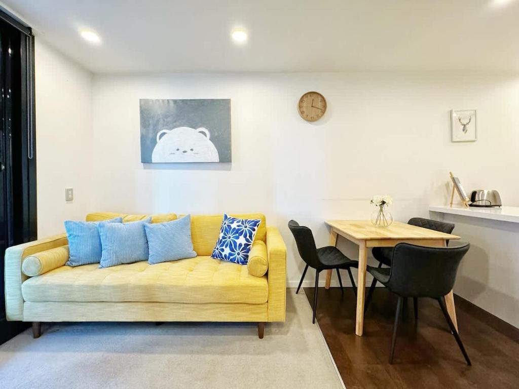 奥克兰Modern 2 Bedroom Beside Skytower & Queen St in The Heart of CBD的客厅里有一张黄色的沙发和一张桌子