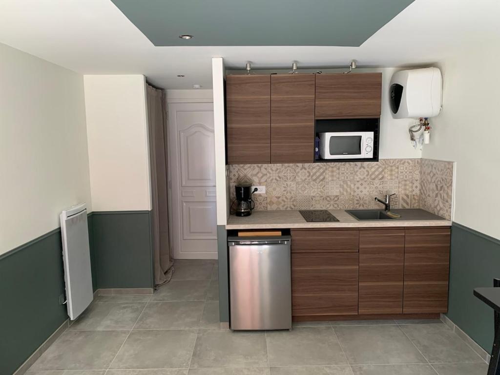 une cuisine avec des armoires en bois et un réfrigérateur en acier inoxydable dans l'établissement Studio idéal pour travail ou vacances dans le sud, à Fos-sur-Mer