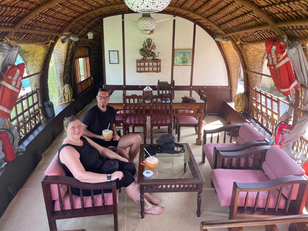 a man and woman sitting in chairs in a room at Thara's Houseboat in Alleppey