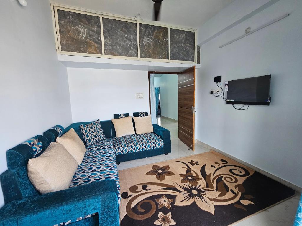 a living room with a blue couch and a tv at Pearl Homes Hyd in Hyderabad