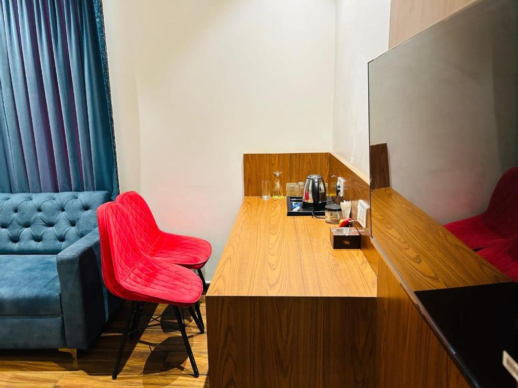Habitación con silla roja y mesa de madera. en Hotel Swarn Bhoomi, en Kānpur