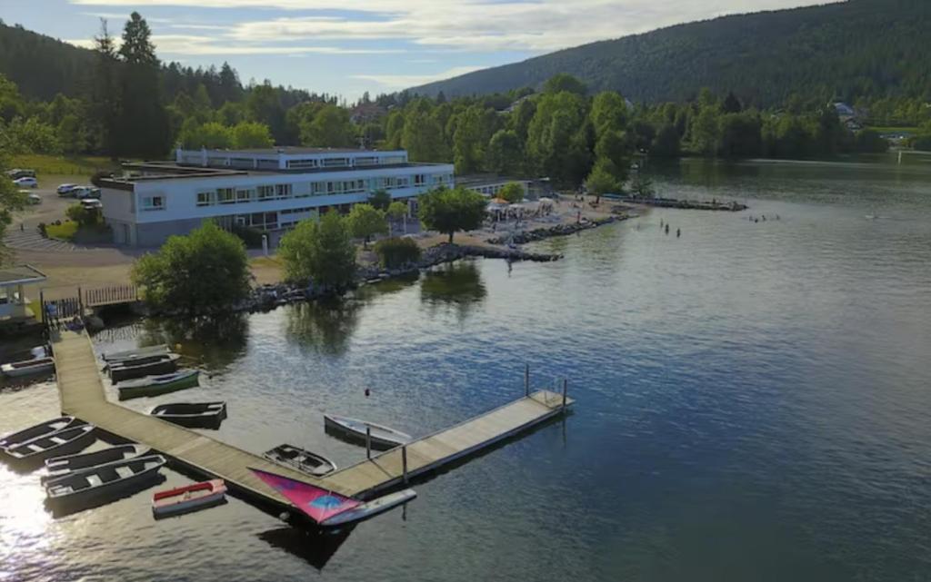 un bâtiment sur un lac avec des bateaux dans l'eau dans l'établissement Appart'Hôtel LIDO au bord de l'eau, à Gérardmer