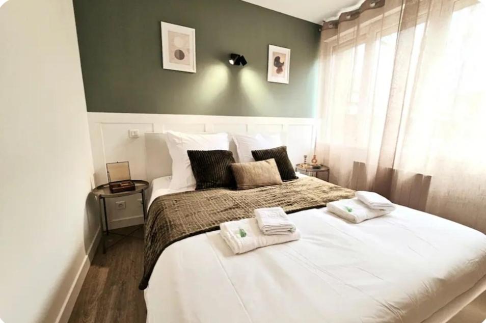 une chambre avec un grand lit avec deux serviettes dessus dans l'établissement Un jardin en ville - L Avenue des Voyageurs, à Boulogne-sur-Mer