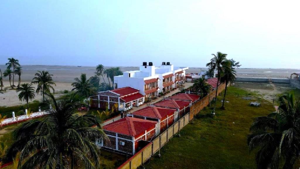 a group of buildings with red roofs and palm trees at Ricardo Beach Resort in Mandarmoni