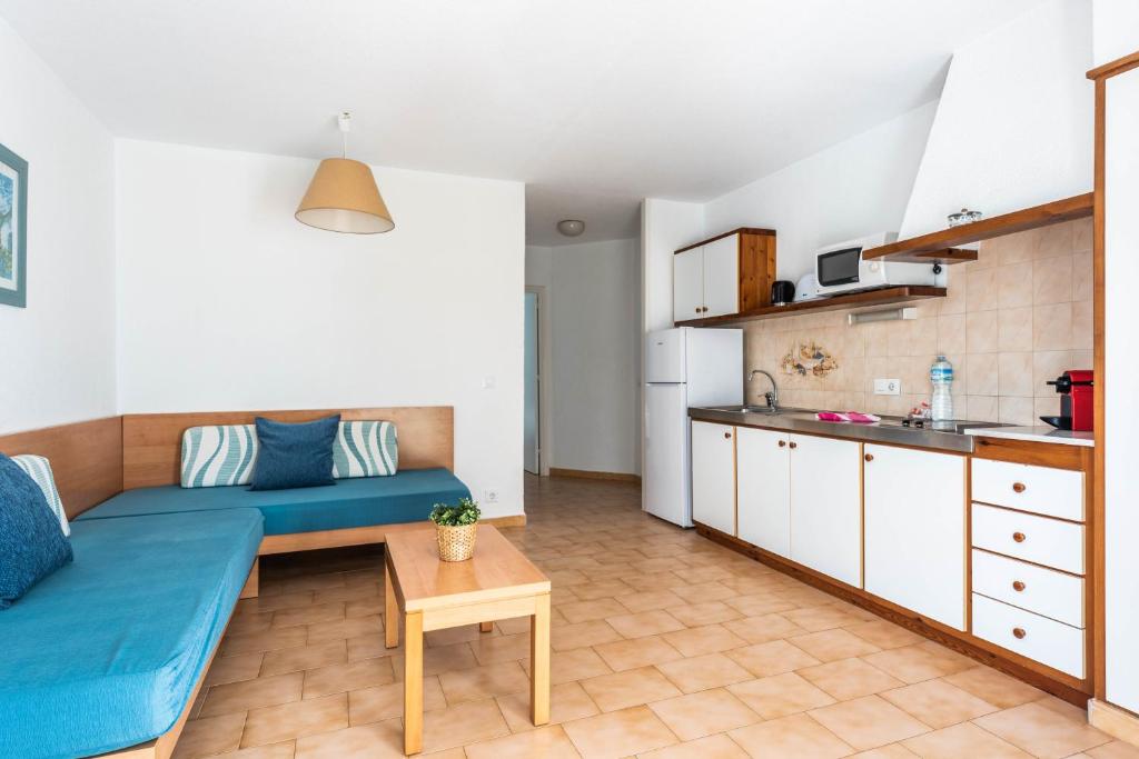 a living room with a blue couch and a kitchen at Apartamentos alta galdana playa in Cala Galdana