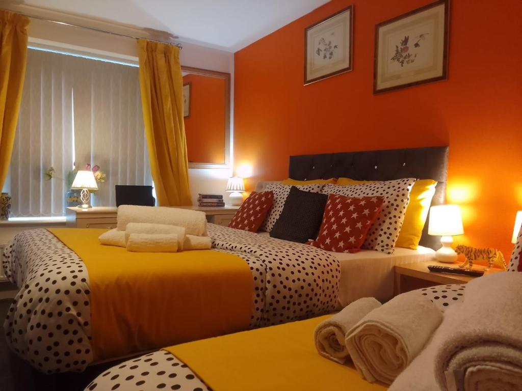 a bedroom with two beds and orange walls at Apartment Sleeps 10 - Pets Parking Ev Charging in Walsall
