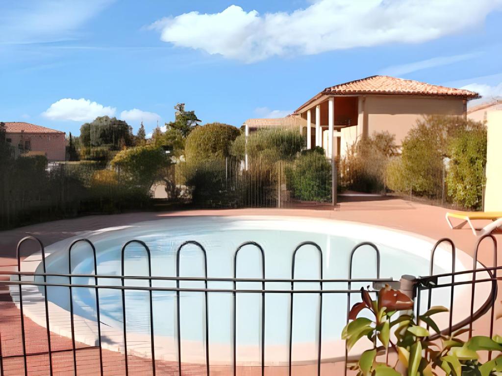 une clôture autour d'une piscine dans une cour dans l'établissement Maison charmante à Aubignan avec piscine partagée, à Aubignan