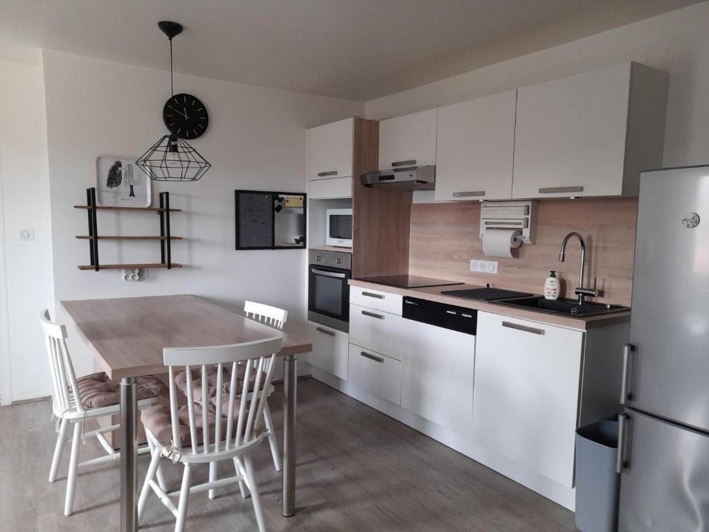 une cuisine avec des armoires blanches et une table et des chaises dans l'établissement Daxou, à Dax