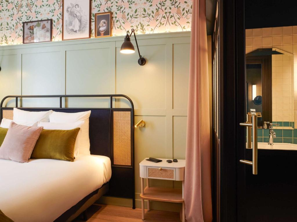 a bedroom with a bed and a bathroom with a tub at Square Lodge Hotel La Roche sur Yon - Handwritten Collection in La Roche-sur-Yon