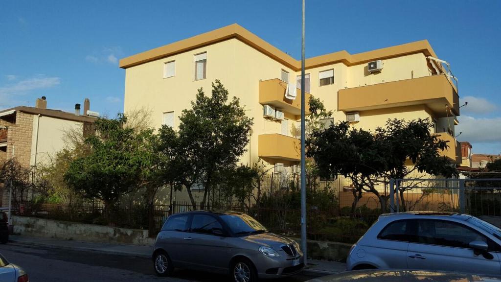 deux voitures sont garées devant un bâtiment dans l'établissement Dalerci Apartment, à Alghero