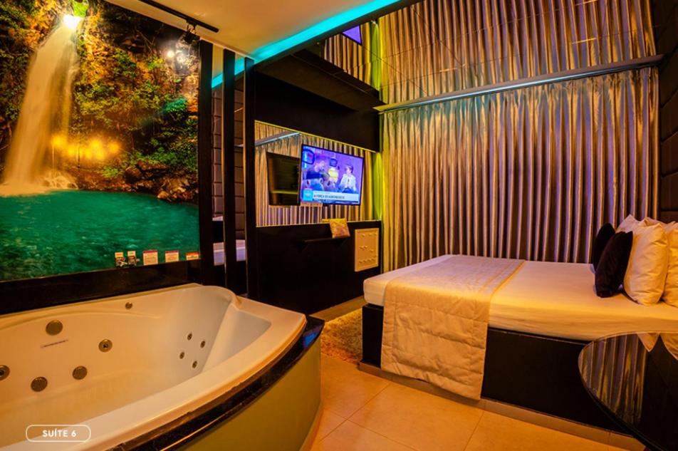 a room with a tub and a bed and a television at Florence Motel - Santo Ângelo-RS in Santo Ângelo