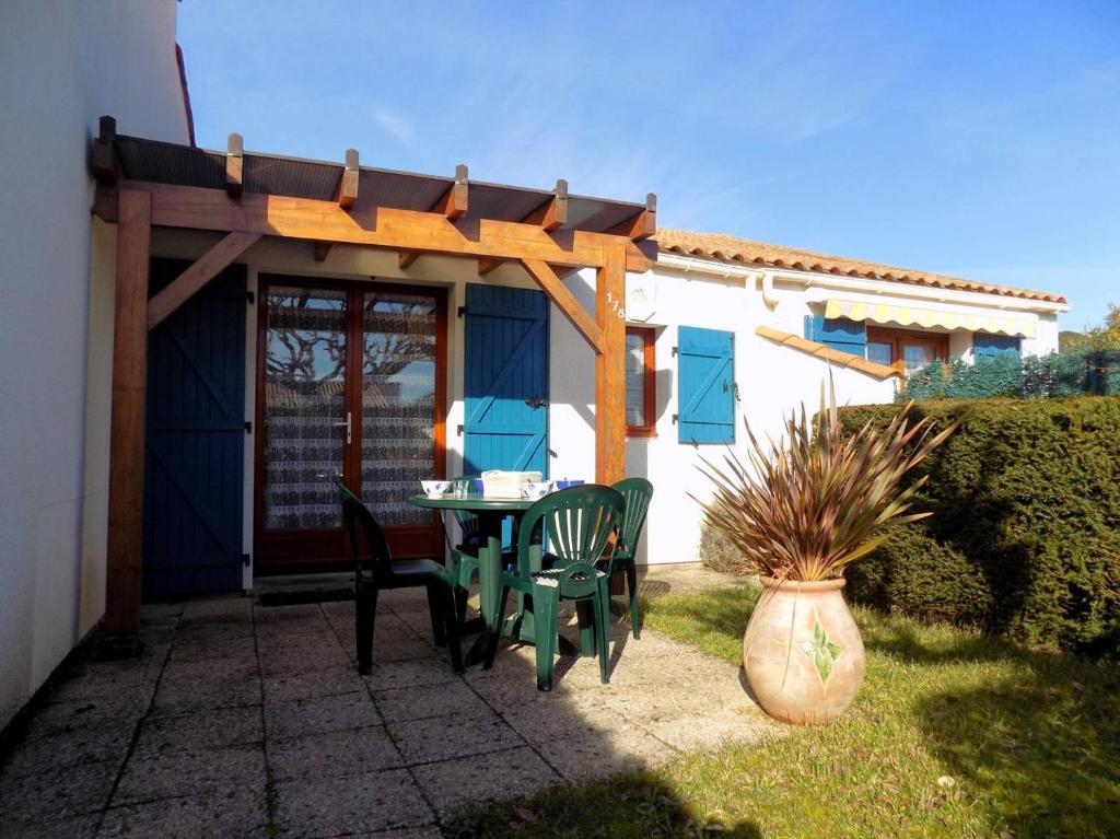 un patio avec une table et des chaises sous une pergola dans l'établissement Saint Palais sur Mer - VILLA MITOYENNE de VACANCES - résidence BOIS SOLEIL, à Puyraveau