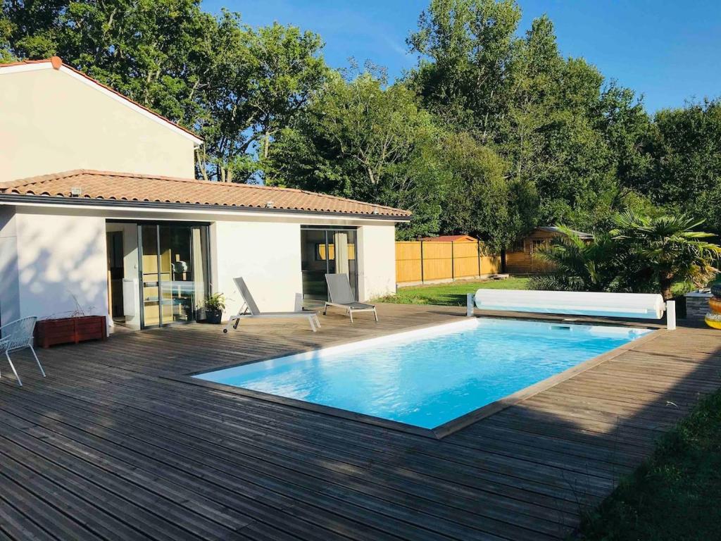 - une piscine sur une terrasse en bois à côté d'une maison dans l'établissement Guest House avec piscine et jardin Privatifs, à Le Pian-Médoc
