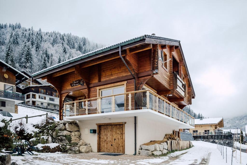 une cabane en rondins dans la neige avec un balcon dans l'établissement Chalet Le Saint Georges, Morzine, proche centre, à Morzine