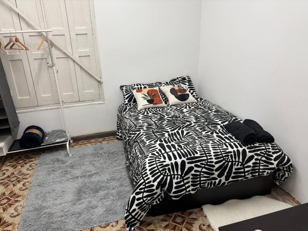 a bedroom with a bed with a black and white comforter at Céntrico a la calle mayor in Alcalá de Henares