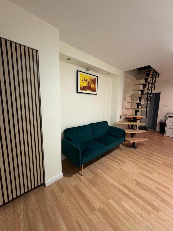 - un salon avec un canapé vert et un escalier dans l'établissement Dépendance COLOMBES, à Saint-Germain-en-Laye