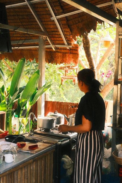 a woman cooking on a stove in a kitchen at Madam Sokha Homesteading in Siem Reap