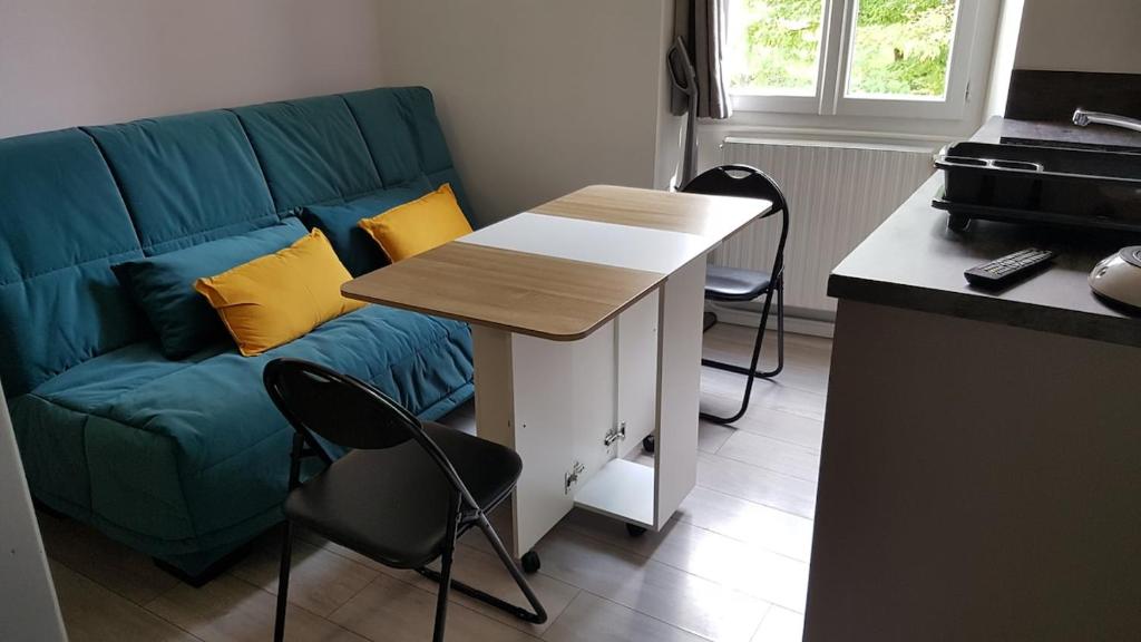 a living room with a blue couch and a table at Studio Georges 1er in Aix-les-Bains