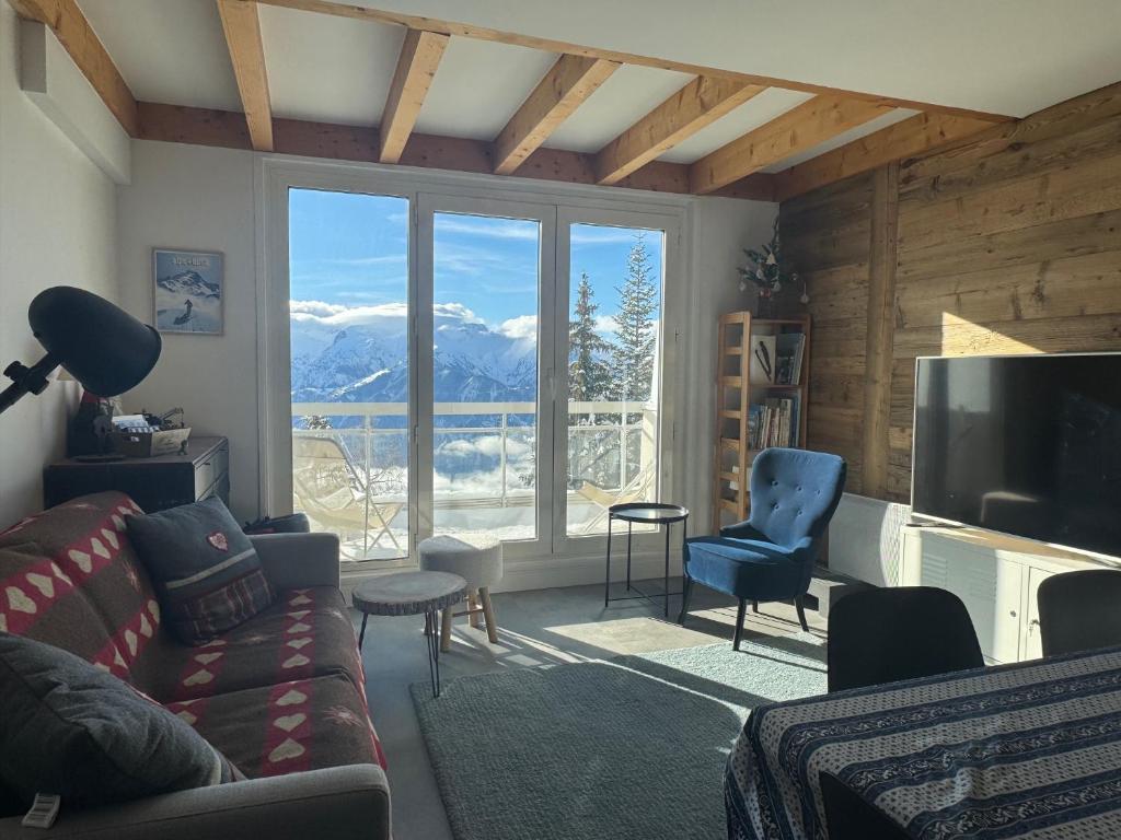 a living room with a couch and a large window at Le Nid Lumiere in LʼHuez