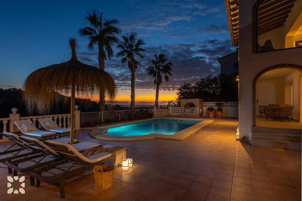 einen Pool mit Stühlen und einem Sonnenschirm auf einer Terrasse in der Unterkunft Villa Bella Primavera by Abahana Villas in Benissa