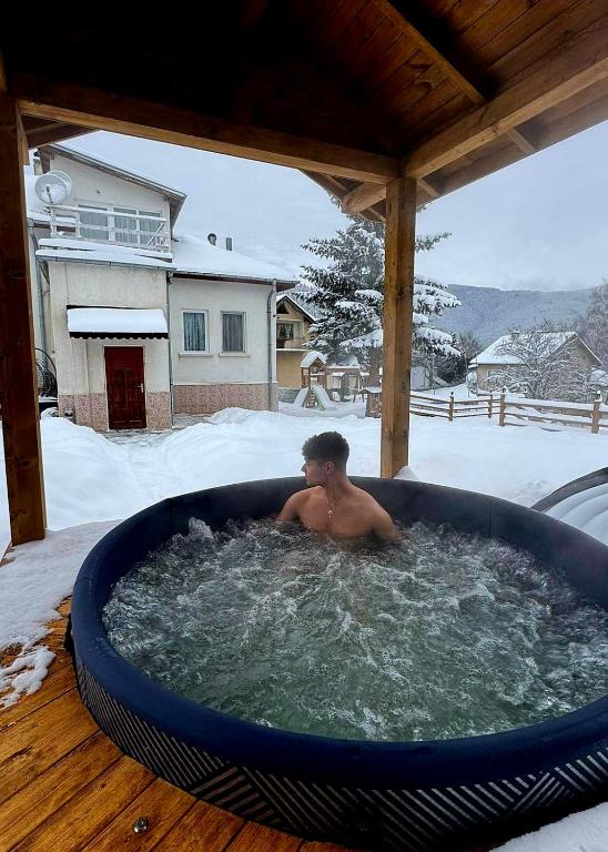 a boy sitting in a hot tub in the snow at Мальовица - къща за гости in Dospey Makhla