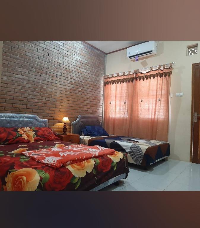 a bedroom with two beds and a brick wall at Homestay Durohman Borobudur in Mendut
