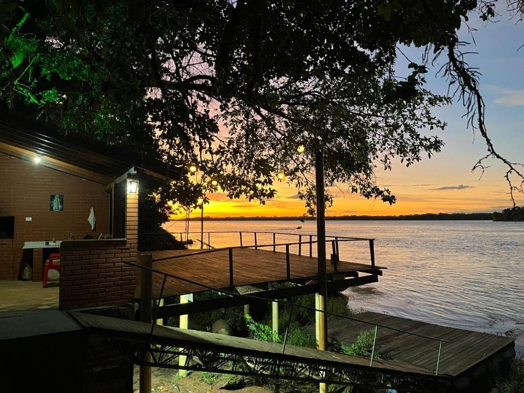 a dock on a lake with a sunset in the background at Pousada Água Doce - Porto Eucalipto in Pôrto São José