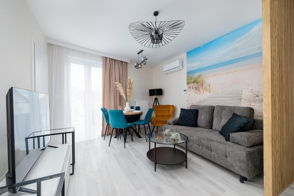 un soggiorno con un divano e un tavolo di Eleganckie Apartamenty Blisko Plaży w Niechorzu z Klimatyzacją w Salonie i Parkingiem by Noclegi Renters a Niechorze