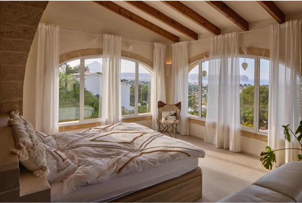 a bedroom with two large windows and a bed at Casa El Sueño in Jávea