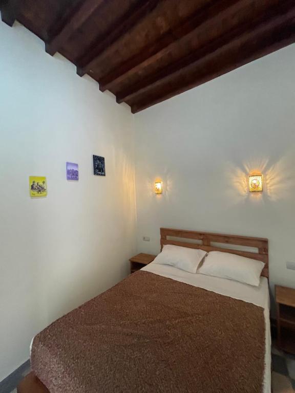- une chambre avec un lit et deux lumières sur le mur dans l'établissement Dar MIMA, à Rabat