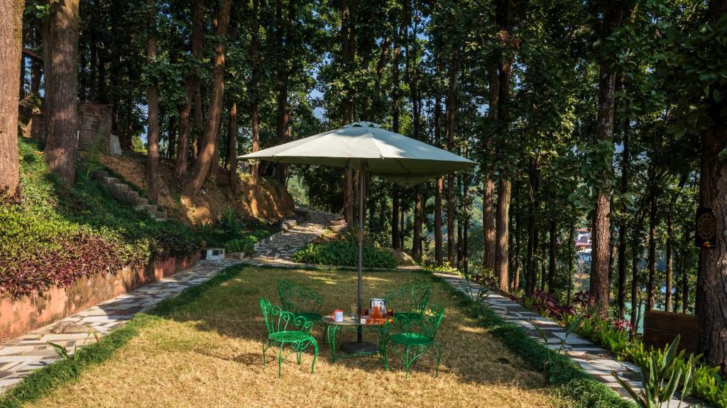 une table et des chaises sous un parasol dans l'herbe dans l'établissement Secret Garden by The StayCationer, à Dehradun