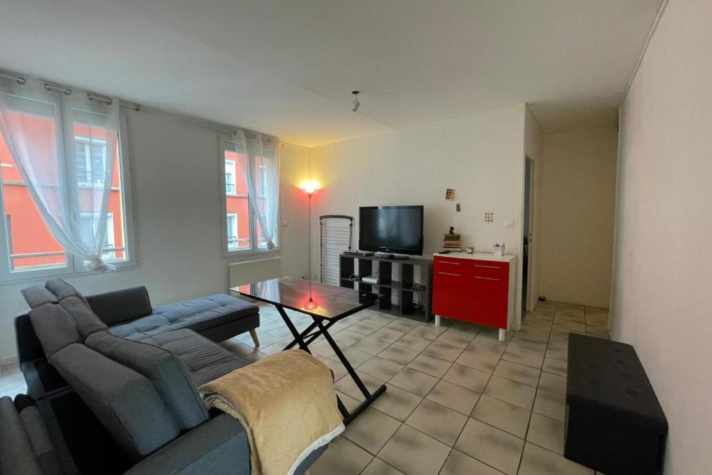 een woonkamer met een bank en een tv bij Le Baheux Urbain in Le Havre