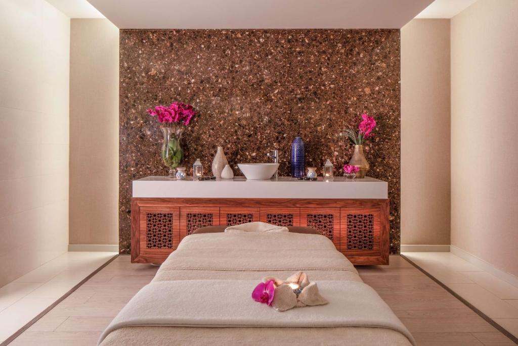 a bedroom with two beds and a table with flowers at Tivoli Carvoeiro in Carvoeiro