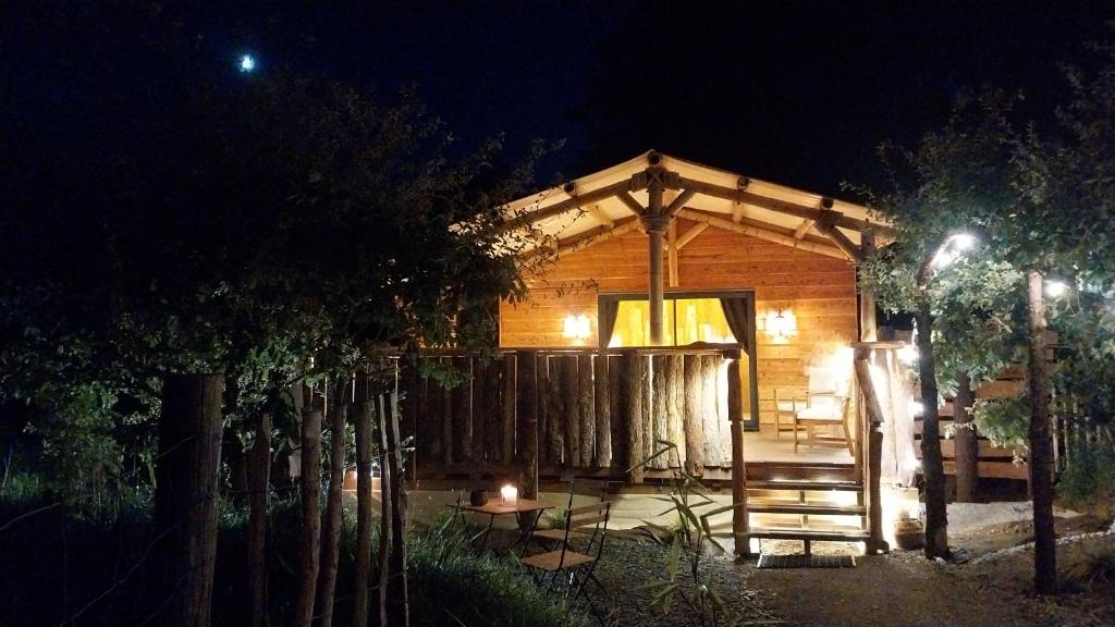 a wooden cabin at night with a fence at L'Entre2rêves in Saint-Maigrin