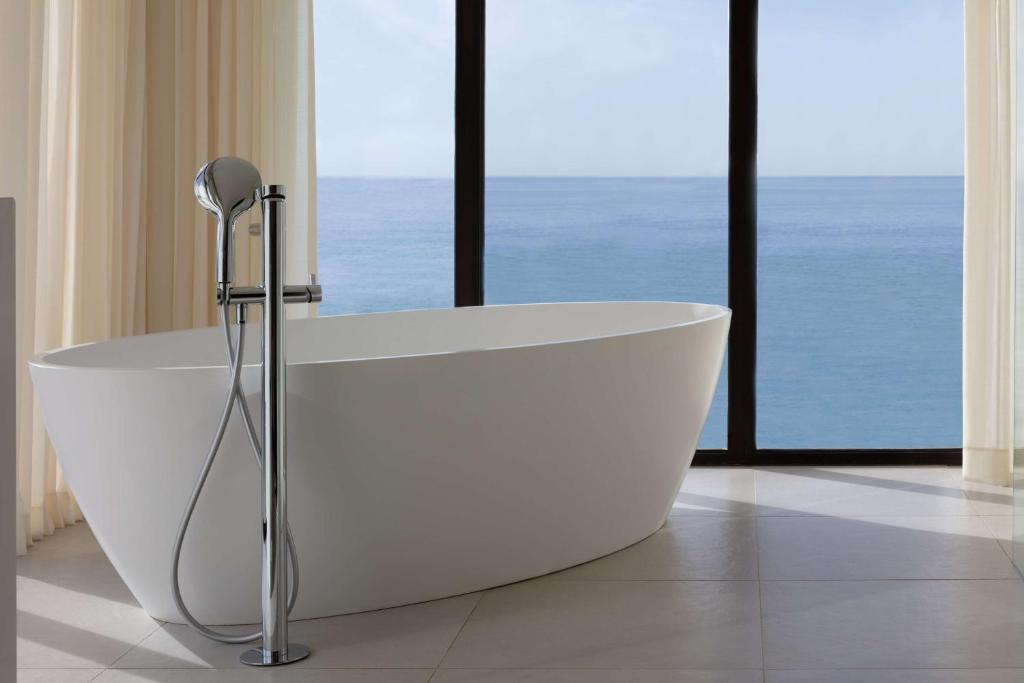 a white bath tub in a bathroom with windows at Tivoli Carvoeiro in Carvoeiro