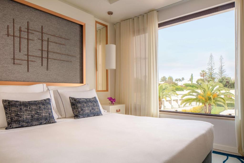 a bedroom with a large bed with a large window at Tivoli Carvoeiro in Carvoeiro