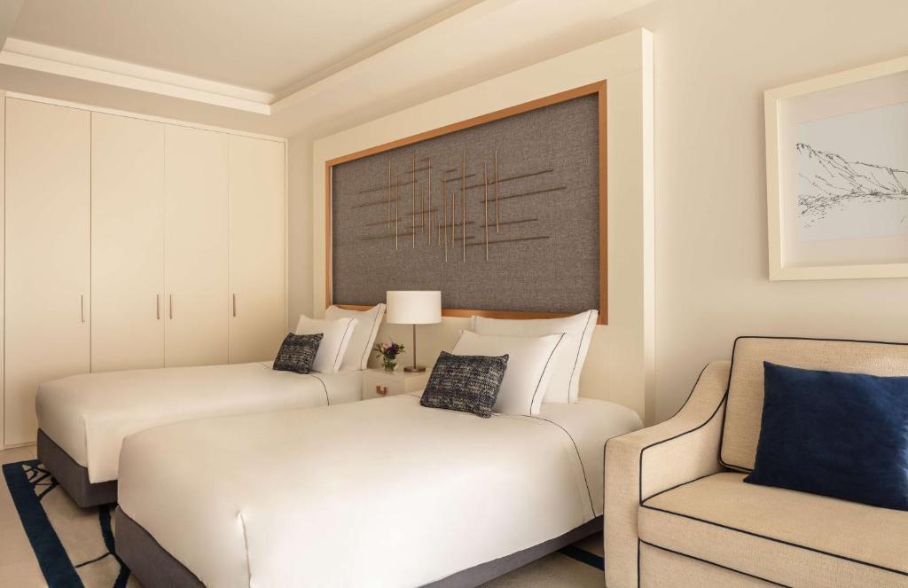 a hotel room with two beds and a chair at Tivoli Carvoeiro in Carvoeiro