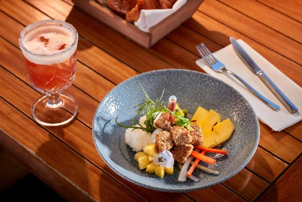 a plate of food on a wooden table with a drink at Tivoli Carvoeiro in Carvoeiro
