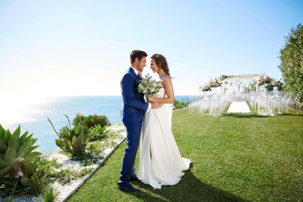 a bride and groom kissing in front of their wedding ceremony at Tivoli Carvoeiro in Carvoeiro