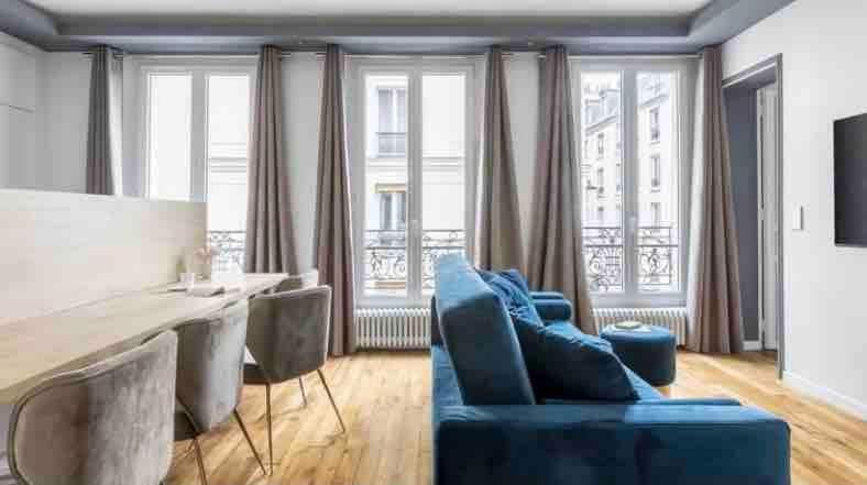 un salon avec un canapé bleu, une table et des chaises dans l'établissement Paris Cozy Apartment 15th Dist- EIFFEL TOUR, à Paris