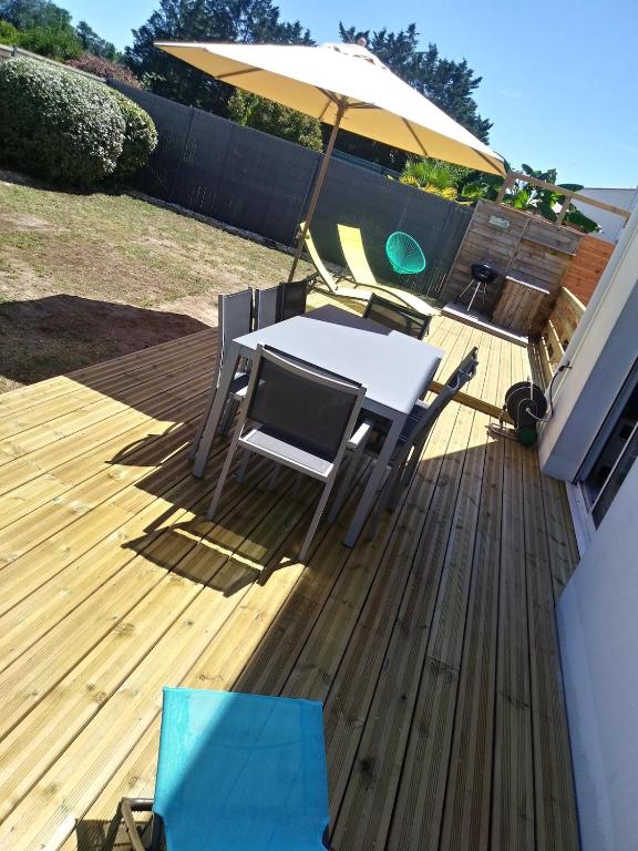 une table et des chaises sur une terrasse avec un parasol dans l'établissement Belle maison 3 chambres avec jardin et piscine Saint-Pierre d'Oléron OCEAN LILI's EYES, à Saint-Pierre-dʼOléron