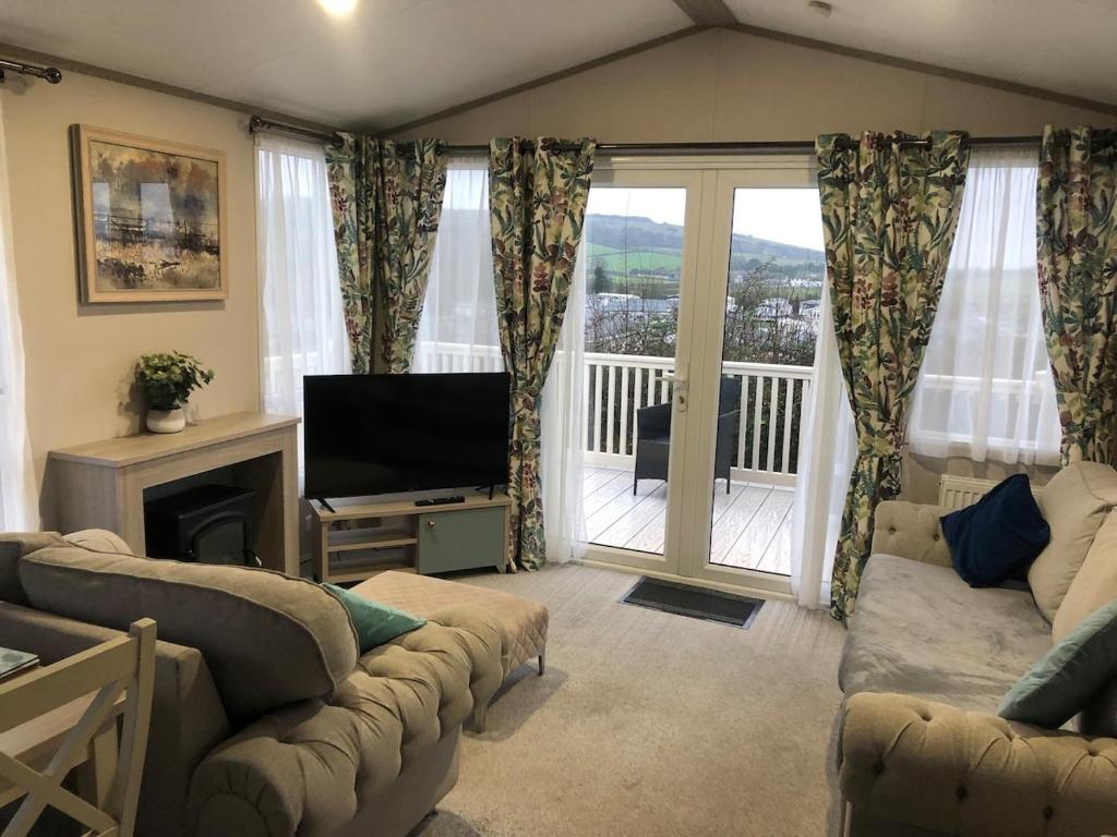 Una sala de estar con un sofá y un televisor y un balcón. en Modern home with amazing views, en Bembridge